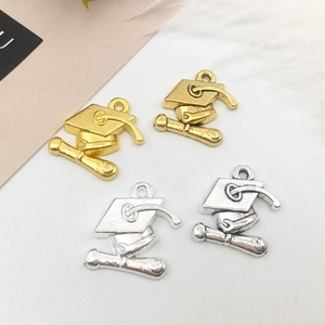Detail of graduation cap and scroll alloy charms in gold and silver for DIY jewelry