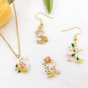 Vergulde alfabet sieradenset met kleurrijke emaille bloemen en decoratieve vlinders