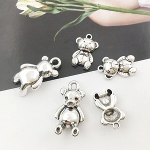 Close-up of antique silver teddy bear pendant with honeycomb texture and bow detail