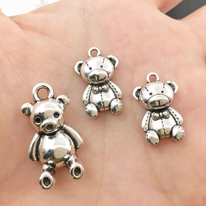 Detailed close-up of three antique silver bear charms held in hand for size visualization