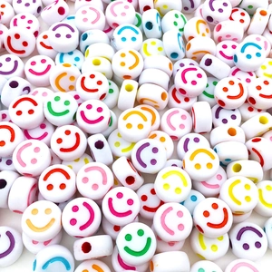 Macro shot of white acrylic smiley face beads with colorful prints for DIY jewelry making