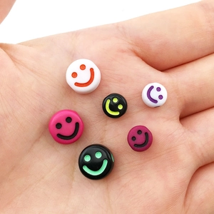 Macro shot of colorful acrylic smiley face beads on hand for DIY bracelet jewelry making