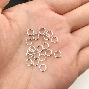 Vue macro d'anneaux de jonction argentés de 4mm dans la main pour montrer leur petite taille