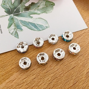 Macro shot of silver spacer beads with colorful rhinestones on a rustic wood surface
