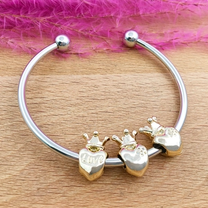 Detail view of silver charm bracelet with three golden crown heart Love pendants