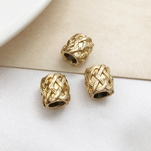 Macro view of gold plated cylindrical beads with woven texture for jewelry making