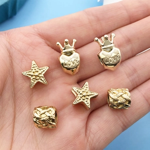 Golden alloy beads set with heart crown and star charms held in hand for size