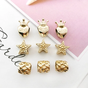 Detailed close-up of gold alloy heart, star, and crown beads for DIY jewelry making