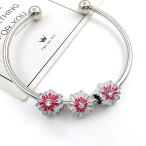 Close-up of silver open bangle with white and red enamel daisy charms and tiny crystals