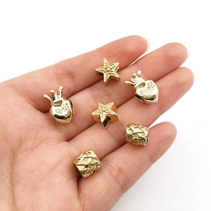 Golden alloy heart crown and star large hole beads held in palm for DIY jewelry making