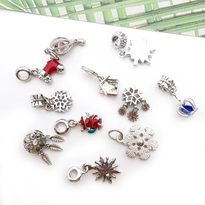 Detailed flat lay of silver Christmas pendants featuring snowflake and stocking enamel designs