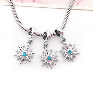 Makroaufnahme von Silber-Schlangenarmband mit drei blauen Kristall-Schneeflockenanhängern