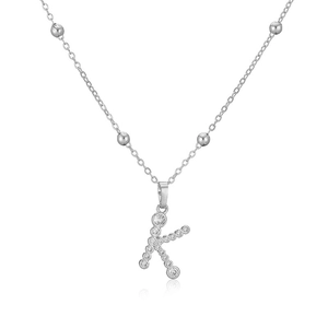 Dettaglio del ciondolo lettera K con zirconi micro-pavé su una collana a sfere d'argento