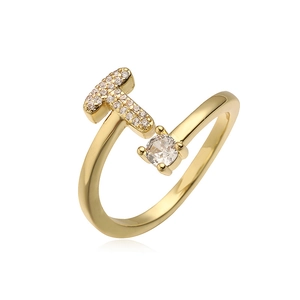 Macro-opname van vergulde ring met letter T in micro-pave en glanzend kristal