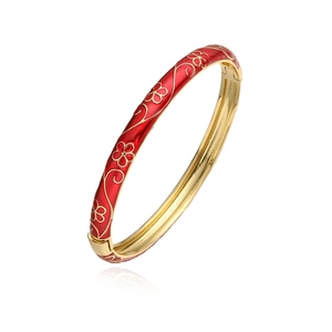 Gros plan détaillé d'un bracelet doré avec émail rouge et motifs floraux de vigne complexes