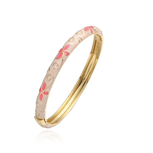 Détail du bracelet jon jonc doré vintage avec émail beige et motifs floraux roses sur blanc