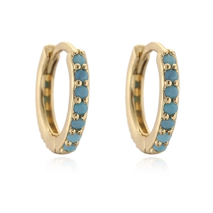 Detail of small gold huggie earrings featuring inlaid turquoise gemstones and secure hinge
