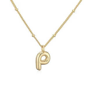 Dettaglio della collana con ciondolo lettera P dorata lucida con effetto bolla d'aria