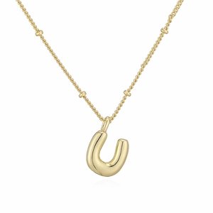 Dettaglio della collana dorata con ciondolo a palloncino lettera U e piccole perline