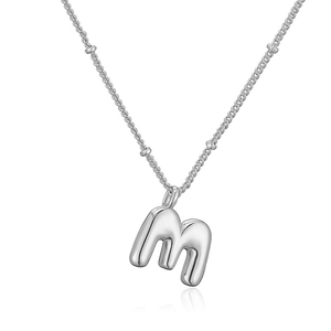 Dettaglio macro del ciondolo a lettera m 3D su una collana con catena a sfere argento