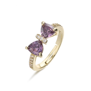 Close-up of golden bow-shaped ring with purple crystals and fine diamond inlay