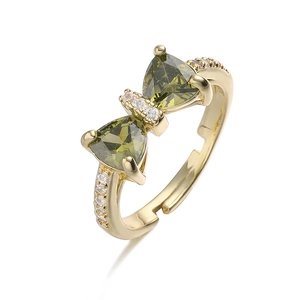 Detailed macro of gold bow ring with olive green gems and white zircon micro-inlay
