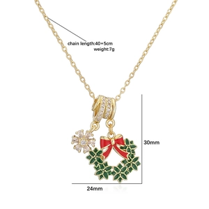 Détail d'un collier de Noël doré avec une couronne verte et un pendentif flocon en zircon