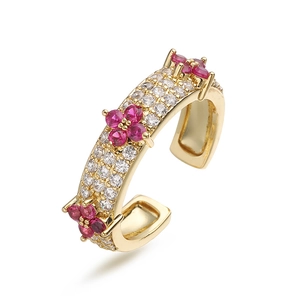 Macro detail of gold four-leaf clover ring featuring pink gemstones and white zircon stones