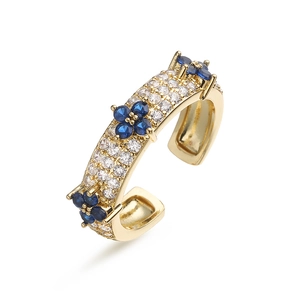 Macro shot of gold adjustable ring featuring white zircons and blue floral patterns