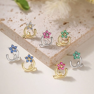 Macro detail of camellia earrings with colorful cubic zirconia and gold petal plating