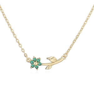 Detailed macro view of golden flower necklace pendant with emerald green gemstones
