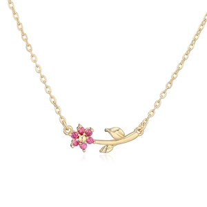 Macro view of gold flower necklace with purple zircon petals and green leaf detail