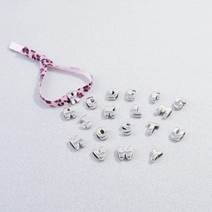 Macro view of silver metallic alphabet charms with pink leopard print ribbon detail