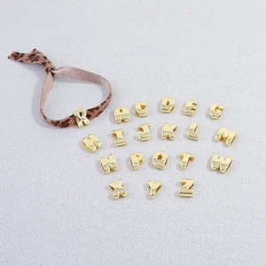 Close-up of golden alphabet beads and leopard print rope showing detailed metallic texture
