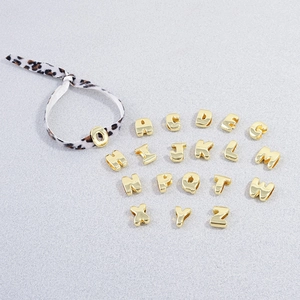 Macro view of gold 3D alphabet beads with polished mirror finish for DIY jewelry