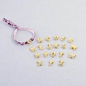 Close-up of golden alphabet beads with leopard print ribbon for DIY jewelry making
