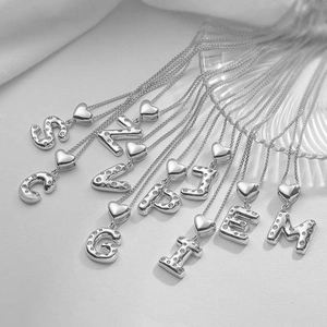 Dettaglio di ciondoli a cuore in argento con lettere in zircone su collane a catena a O