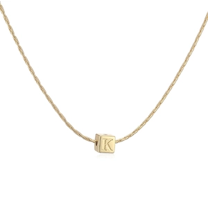 Gros plan d'un pendentif cube plaqué or 18 carats avec lettre K sur une chaîne à maillons