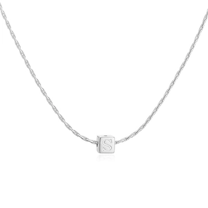 Détail macro du pendentif carré argenté avec lettre S gravée sur chaîne polie