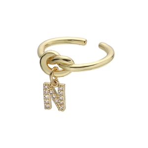 Detailopname van goudkleurige gedraaide ring met een zirkoon bezette letter N hanger