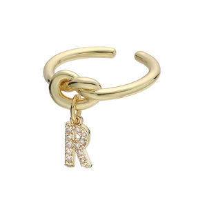 Detail van gouden knoopring met bungelende letter R hanger bezet met zirkonia