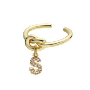 Macro detail van gouden gedraaide ring met sprankelende zirkoon letter S hanger