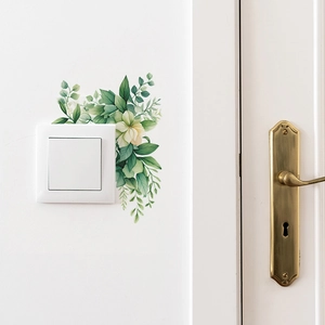 Détail de stickers muraux floraux avec feuilles vertes autour d'un interrupteur blanc sobre