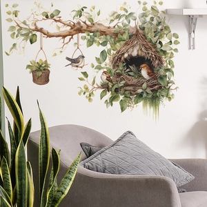 Watercolor tree branch wall sticker with cute birds and nest over a grey sofa