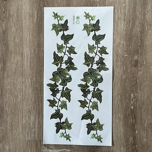 Detailed macro view of lifelike green ivy vine wall stickers on light wood background