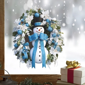 Christmas wreath with white snowman, blue bow and pine needles on a snowy window sill