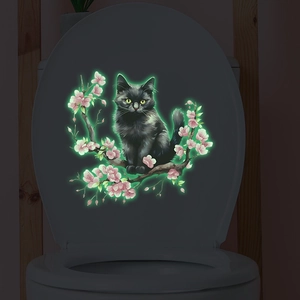 Luminous wall sticker with black cat and cherry blossom glowing on a toilet lid