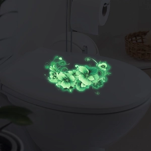 Green luminous floral wall stickers glowing on a toilet lid in a dark bathroom setting