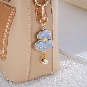 Chinese style blue embroidered gourd charm with golden trim on a brown leather handbag