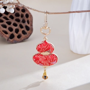 Close-up of red satin gourd pendant with gold embroidery and enamel cloud detail